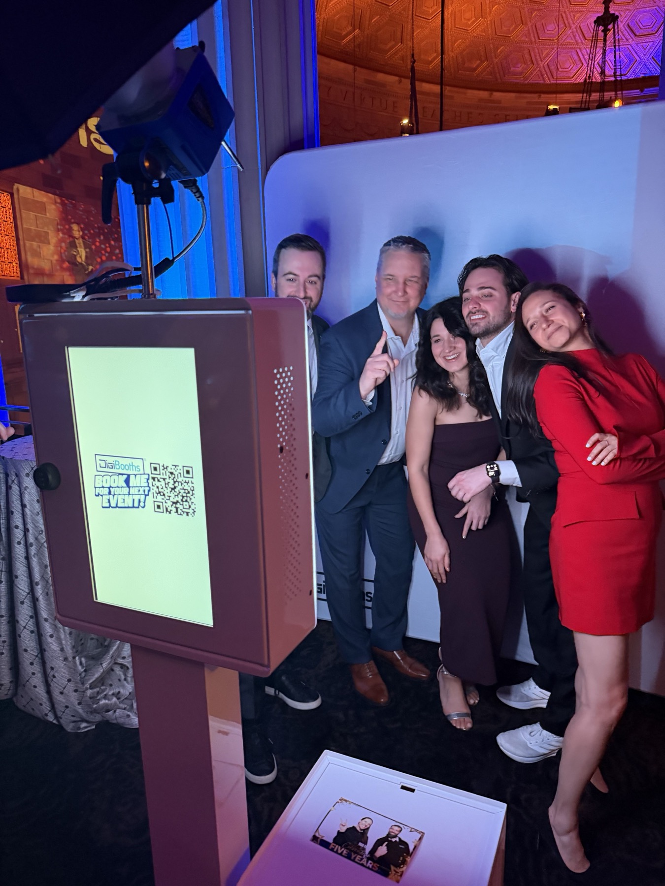The classic photo booth in use at an NYC gala, guests reviewing their print