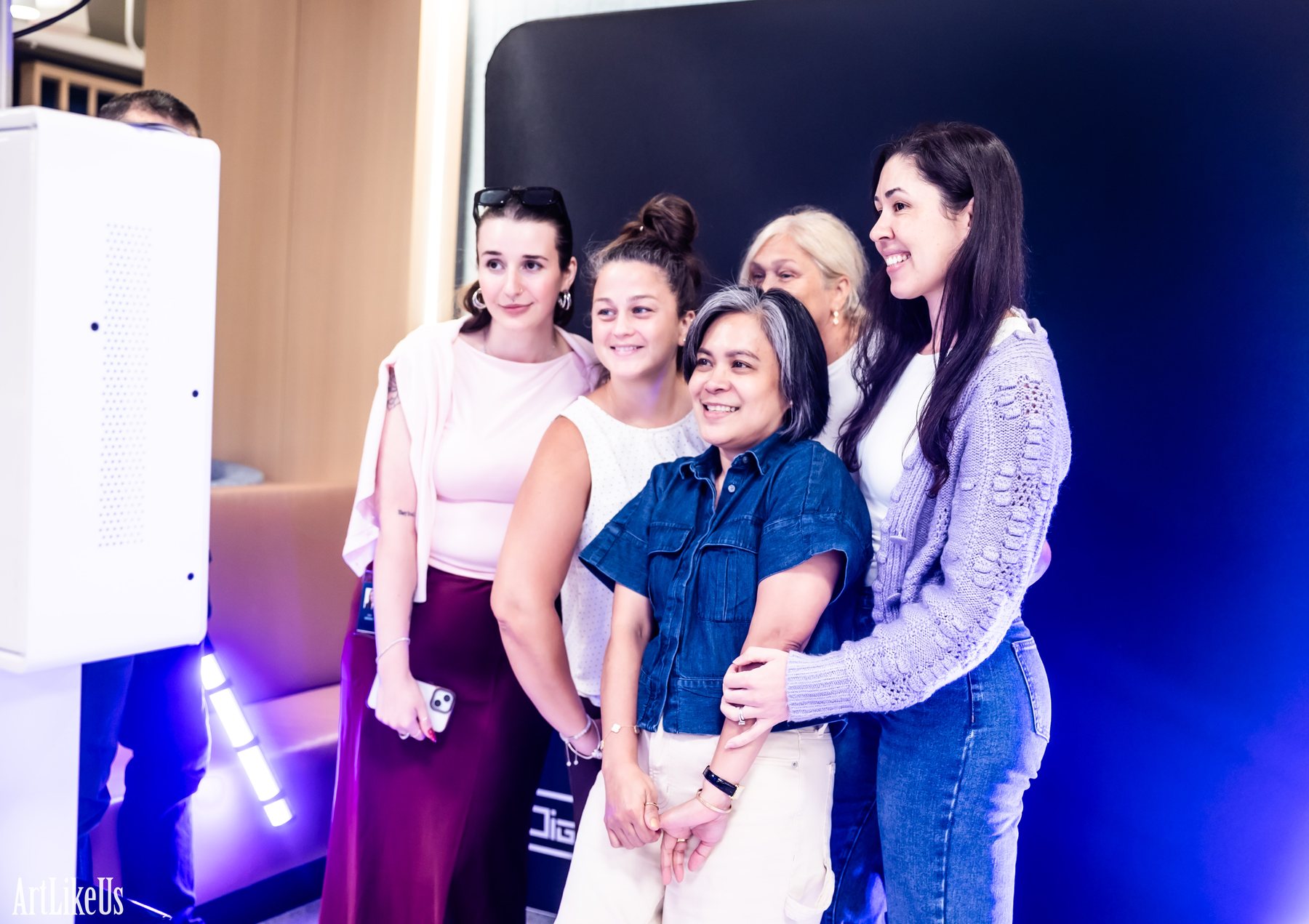 A group of colleagues smiling together in front of the DigiBooths light painting backdrop