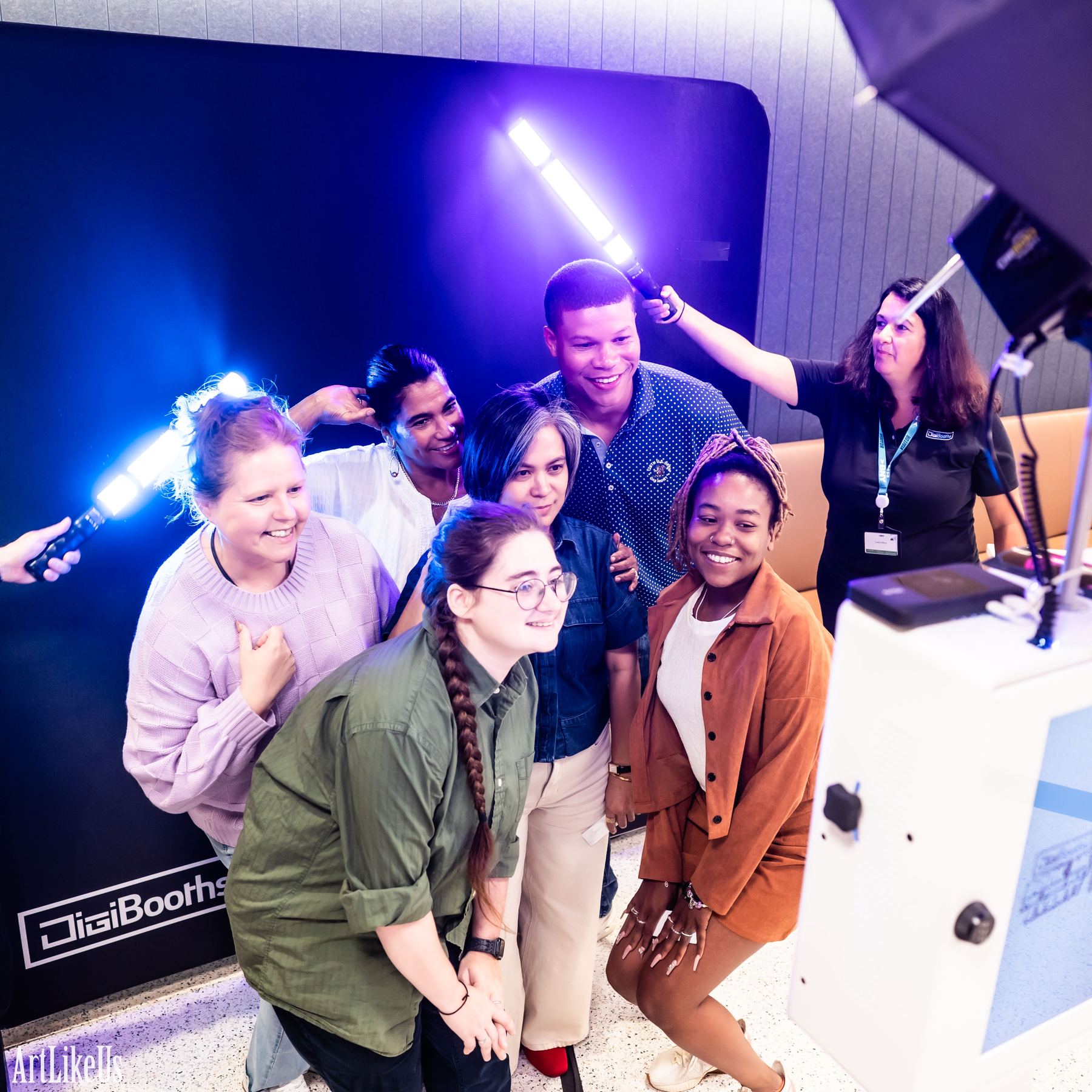 A group of guests laughing together in front of the DigiBooths backdrop after seeing their light painting result