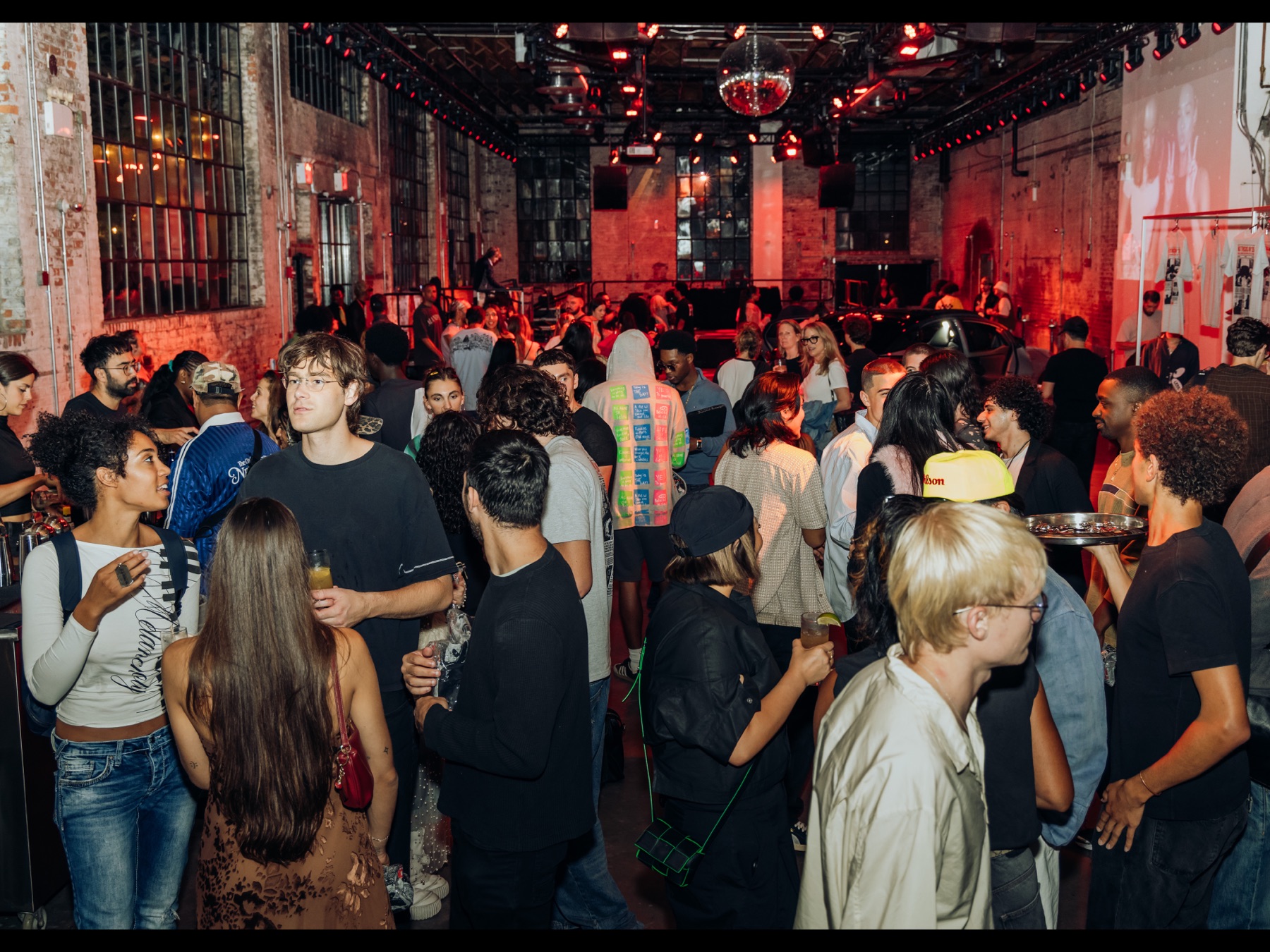 The crowd filling the red-lit, exposed-brick venue at the Hypebeast x Toyota NYFW party, disco ball overhead