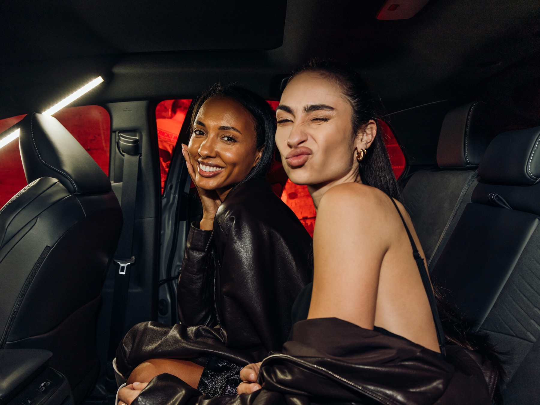 Two guests laughing together in the back seat of the Toyota C-HR during the in-car photo capture