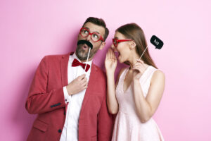 A couple using photo booth props to make their photo more fun.