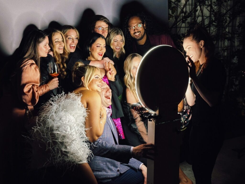 A group of friends at a corporate event trying a photo booth. 