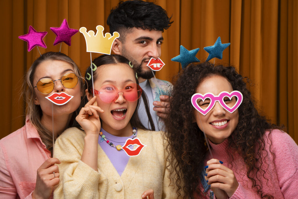 .College friends posing in the photo booth rented by their university for an event.