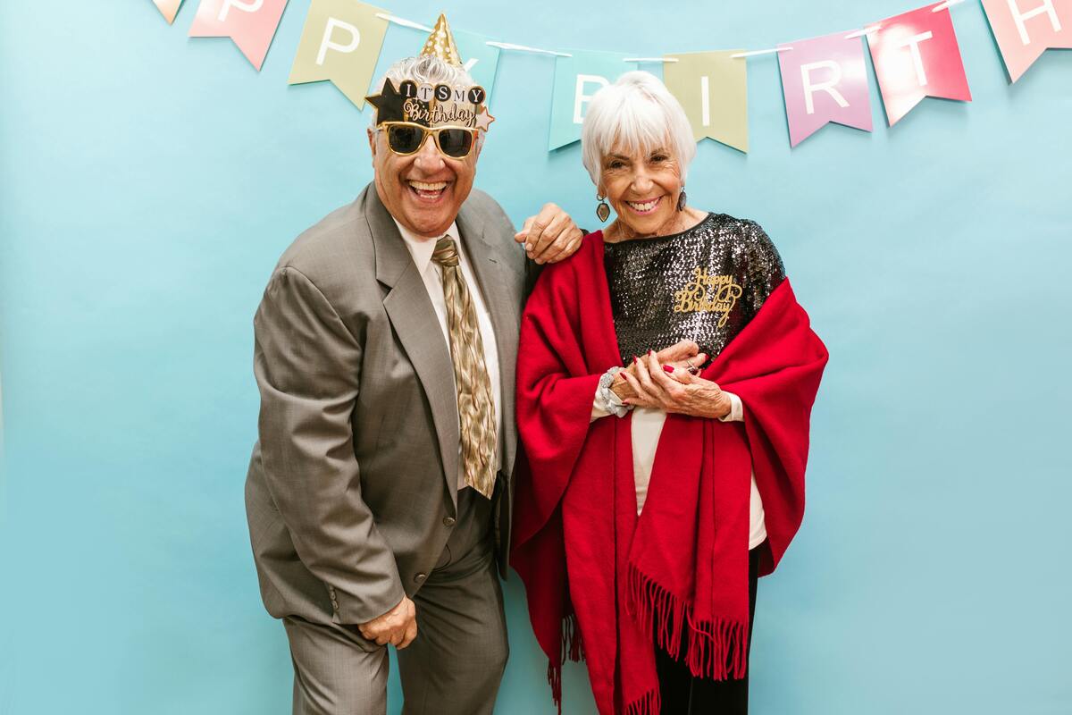 A senior couple posing in a photo booth setup.