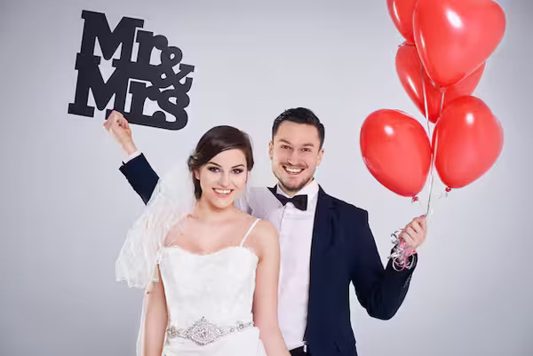 A married couple holding wedding photo booth props