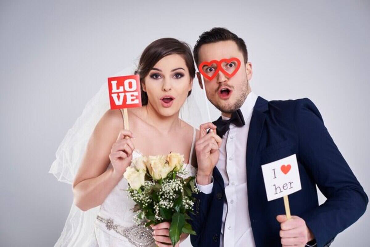 Married couples taking pictures in a wedding photo booth