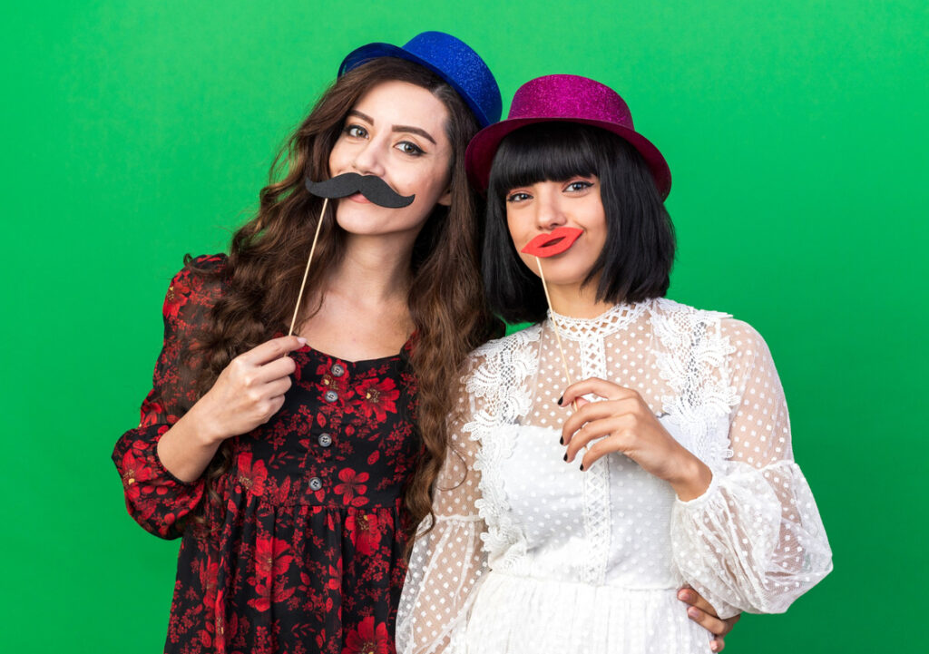 Cousins posing in a photo booth with a green screen background.