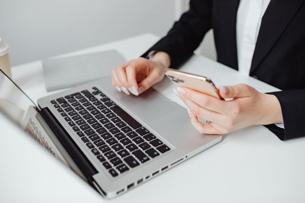 A woman using a laptop and phone