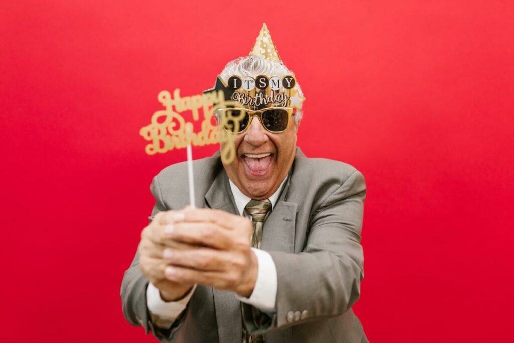 a man in gray suit smiling in photo booth solid red backdrop