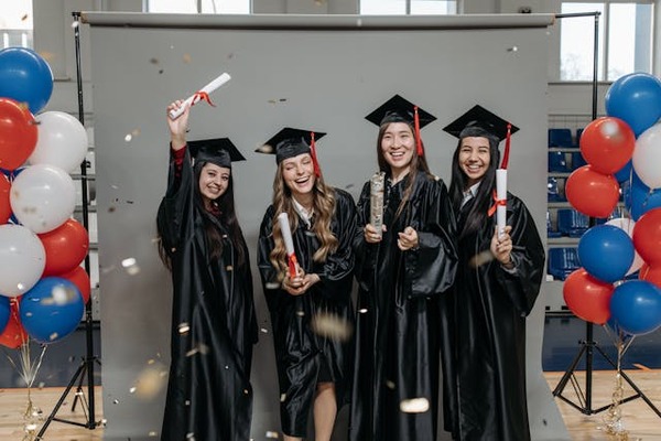 happy graduates standing in photo booth with solid gray backdrop