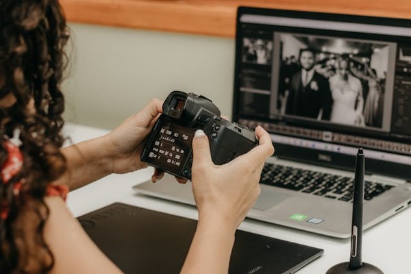 photographer holding camera over laptop