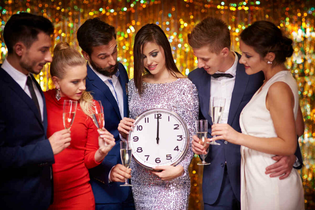 Group of people at party holding clock and champagne.