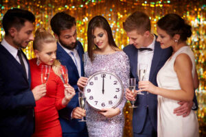 Group of people at party holding clock and champagne.