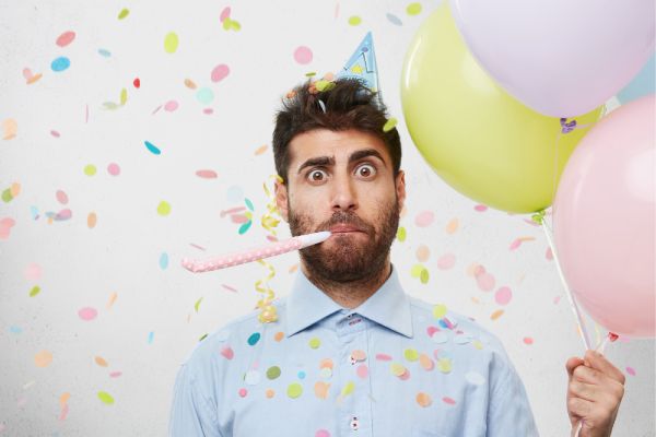 guy with party hat and confetti taking a picture in a photo booth