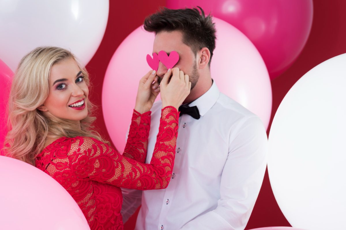 wife making funny face expression of paper hearts in wedding photo booth