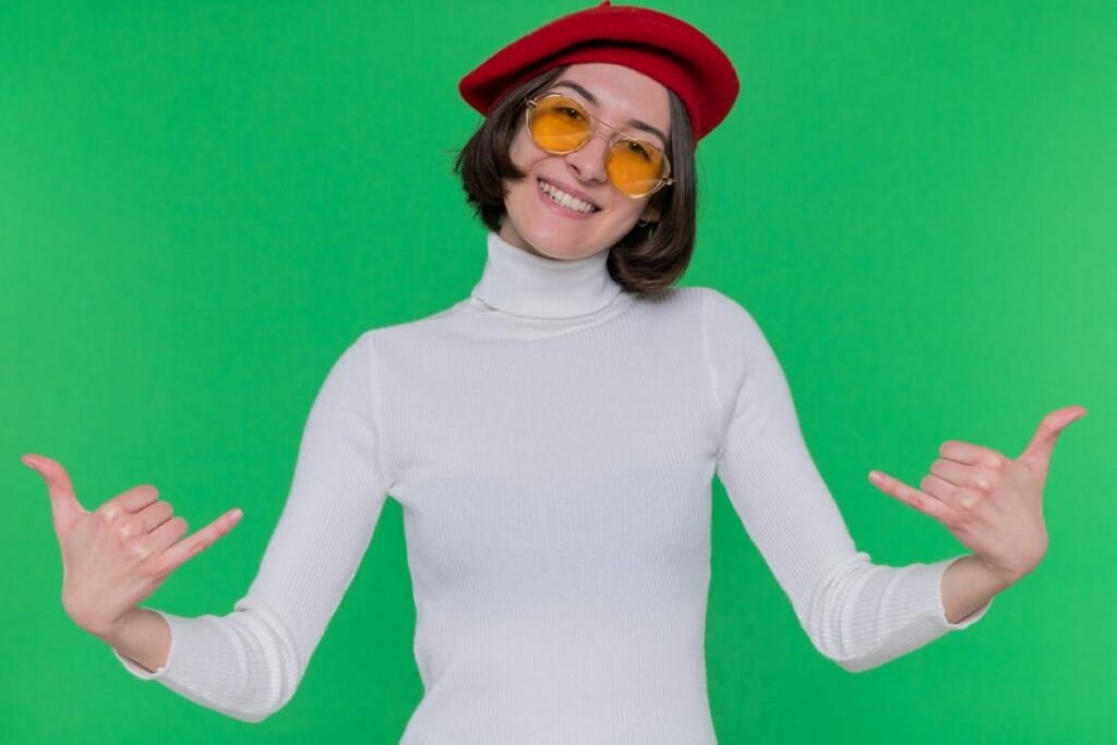 young woman with short hair in white turtleneck wearing beret pose in 360 photo booth