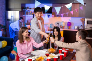 Friends celebrating at home with drinks, snacks, and decorations.