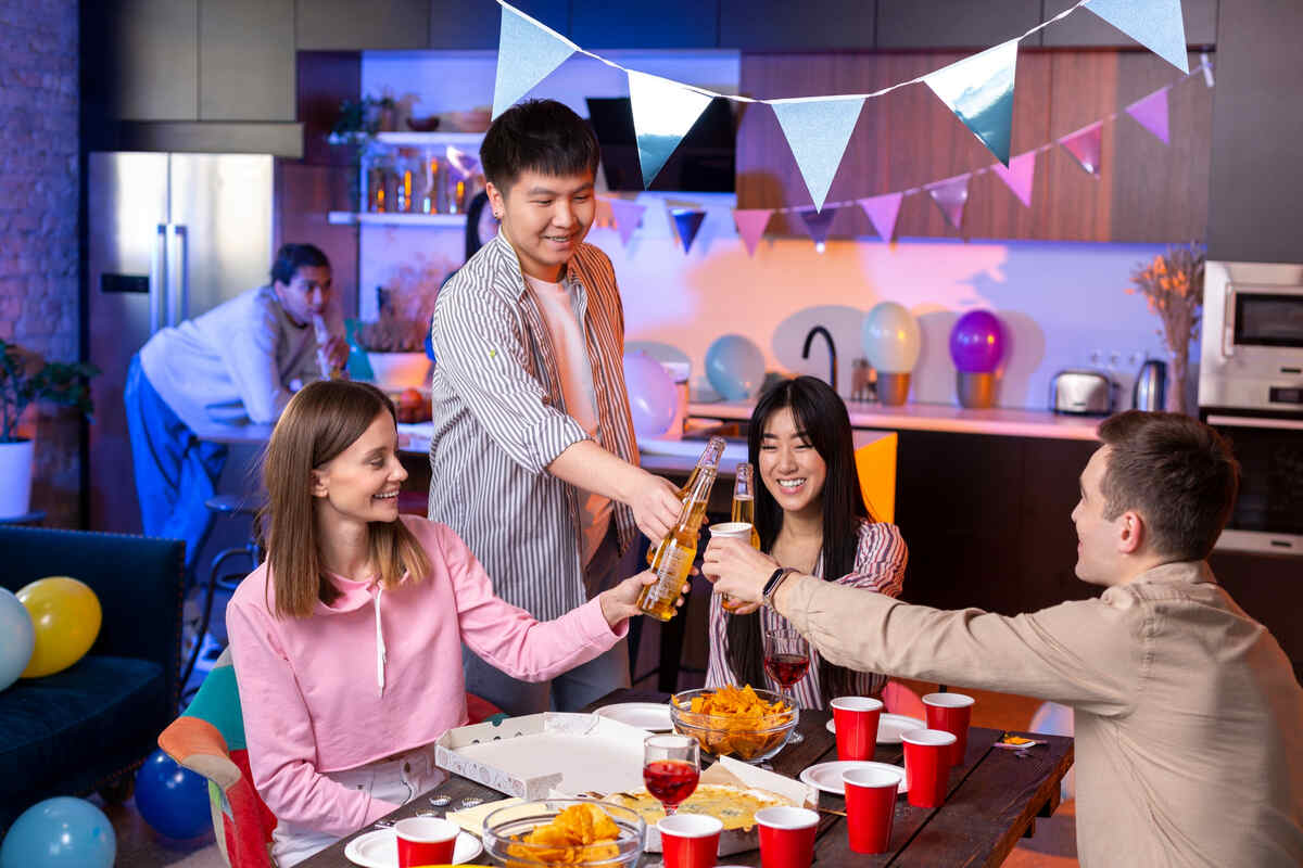 Friends celebrating at home with drinks, snacks, and decorations.