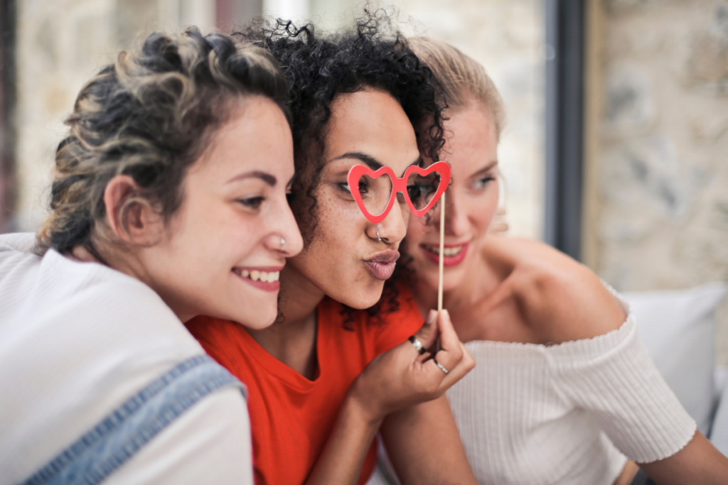  Three women taking a picture at a photo booth using fun props.
