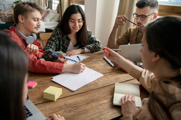 Group of young adults planning together around wooden table.