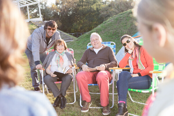 Family relaxing outdoors on lawn chairs during sunny reunion.