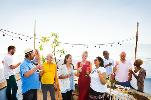 Diverse group enjoying beachside reunion with food and drinks.