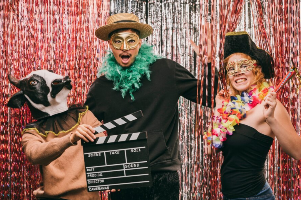 Three people posing in a photo booth while wearing fun props