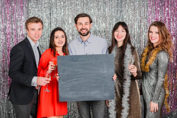 family posing in a festive photo booth with a blank sign at a stylish family reunion