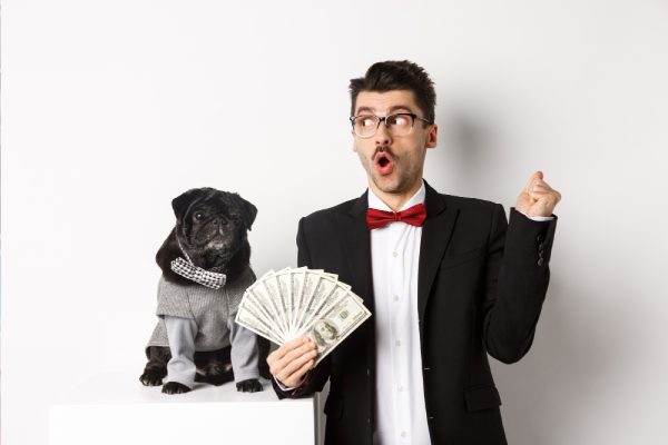 man in tuxedo and pug in costume posing at a reunion photo booth with cash prop