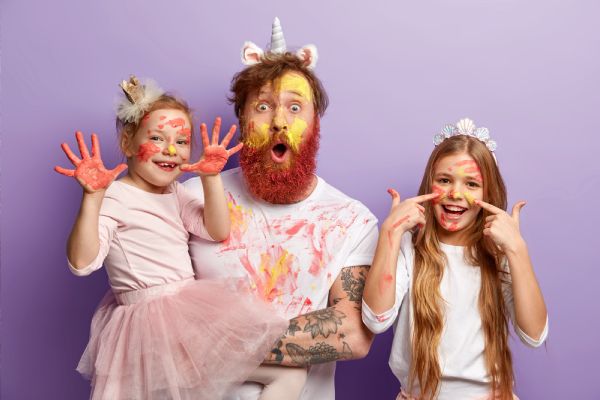 playful dad and daughters covered in paint having fun at a whimsical family reunion photo booth