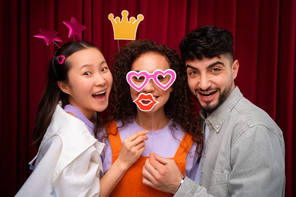 three friends posing with fun props in a colorful reunion photo booth setup