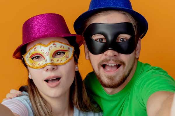 young couple striking a fun pose in a family reunion photo booth with glittery hats and masks